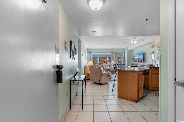 interior space with ceiling fan, dishwasher, brown cabinetry, a peninsula, and open floor plan