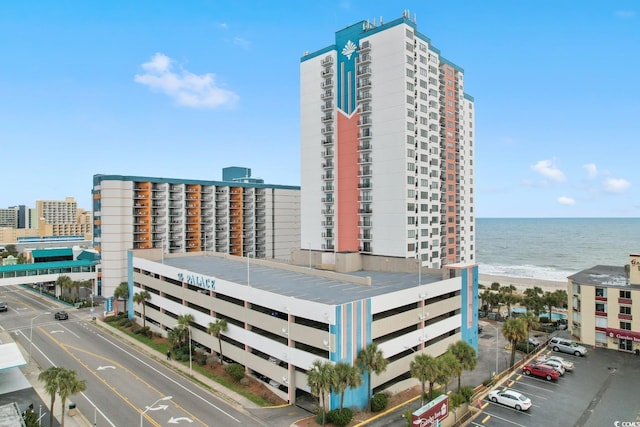 view of property with a water view, uncovered parking, and a view of the beach