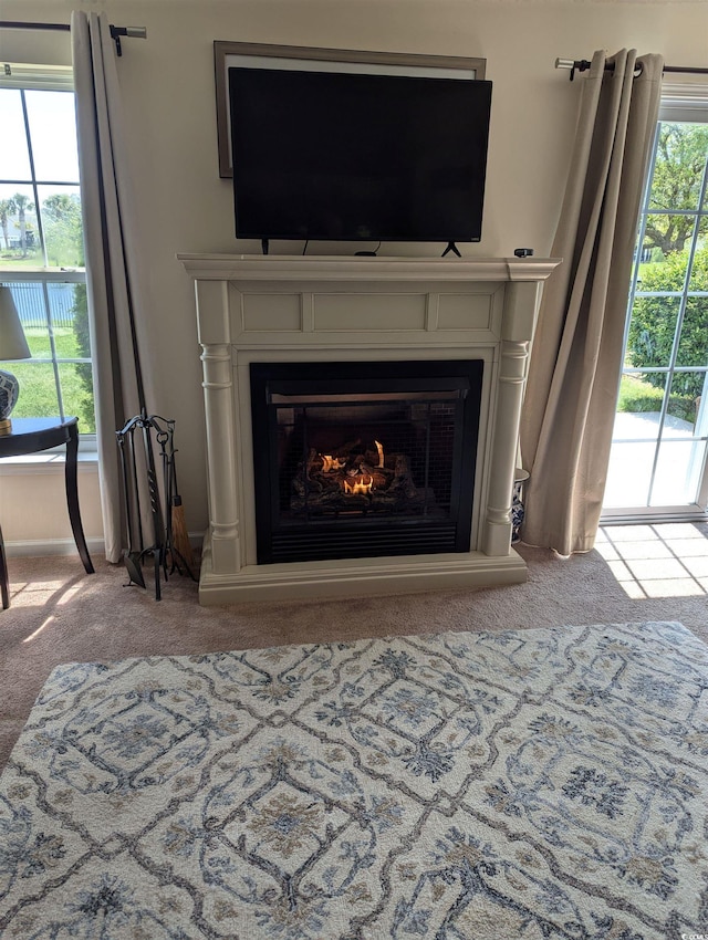 detailed view of carpet floors and a glass covered fireplace