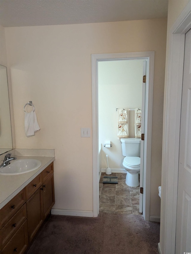 bathroom with vanity, baseboards, and toilet