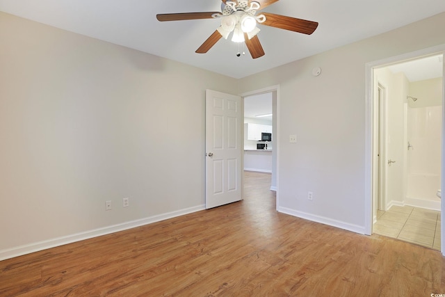 empty room with a ceiling fan, light wood-type flooring, and baseboards