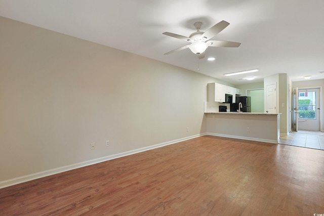 unfurnished living room featuring light wood-type flooring, ceiling fan, and baseboards
