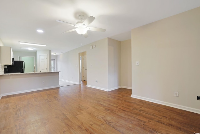 unfurnished living room with ceiling fan, wood finished floors, baseboards, recessed lighting, and a sink