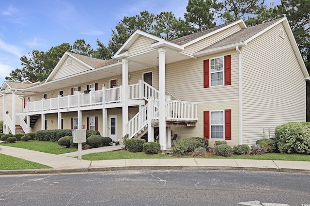 view of front of home with stairway and a shingled roof