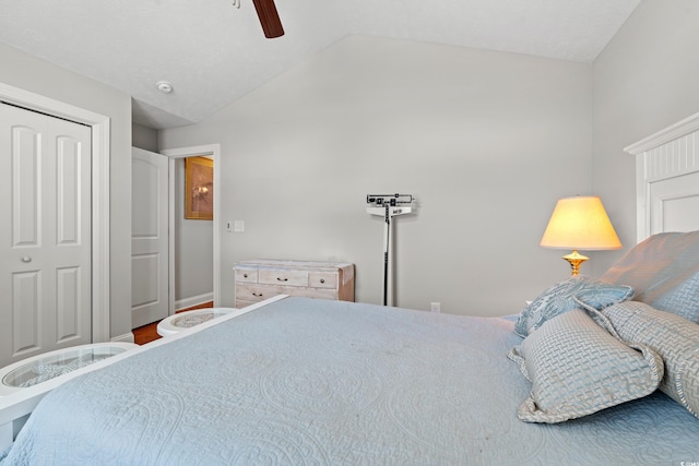 bedroom with a ceiling fan, vaulted ceiling, wood finished floors, baseboards, and a closet