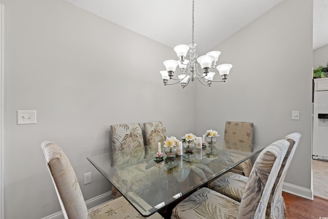 dining area featuring baseboards, lofted ceiling, wood finished floors, and a chandelier