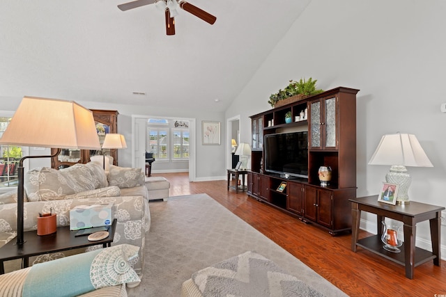 living area with baseboards, ceiling fan, high vaulted ceiling, and wood finished floors