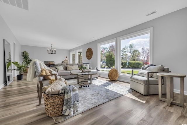 living area with visible vents, light wood finished floors, and a notable chandelier