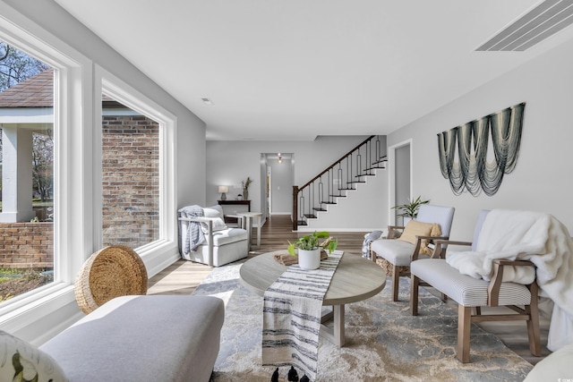 living area featuring baseboards, visible vents, wood finished floors, and stairway