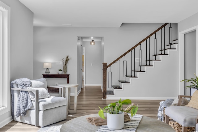 living room featuring stairs, baseboards, visible vents, and wood finished floors