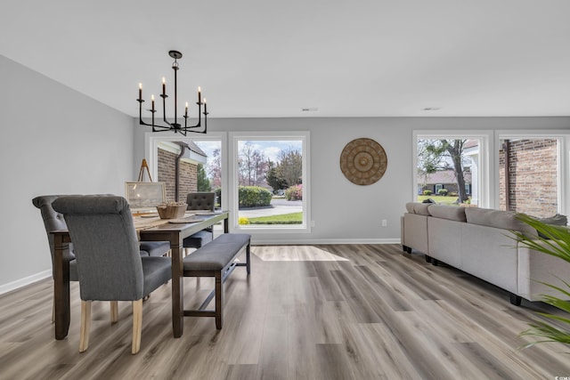 dining space featuring an inviting chandelier, baseboards, and light wood-type flooring