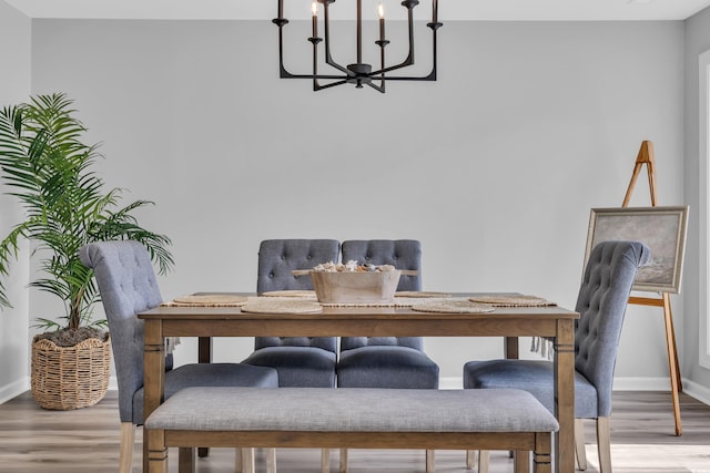 dining area with baseboards, wood finished floors, and a notable chandelier