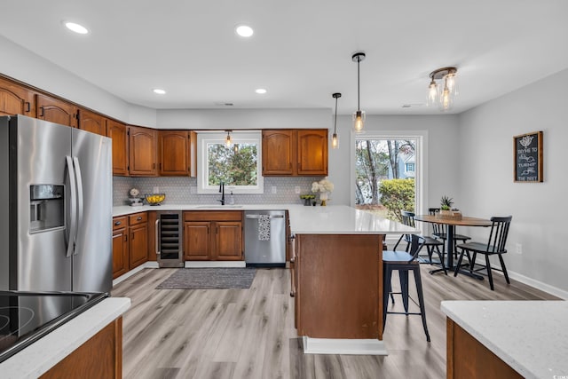 kitchen with a breakfast bar area, a sink, a peninsula, beverage cooler, and stainless steel appliances