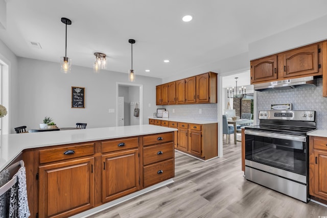 kitchen with brown cabinetry, tasteful backsplash, light countertops, stainless steel electric stove, and under cabinet range hood