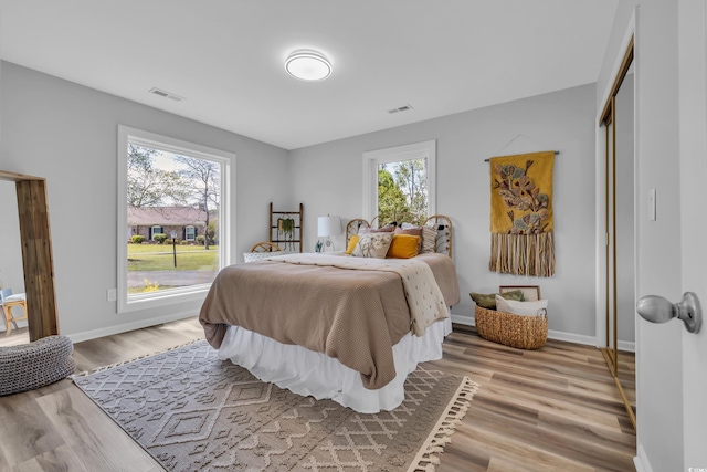 bedroom with baseboards, visible vents, and light wood-style flooring