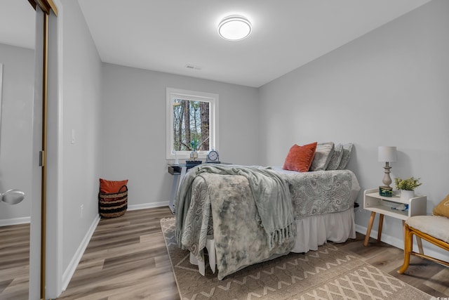 bedroom featuring visible vents, baseboards, and wood finished floors