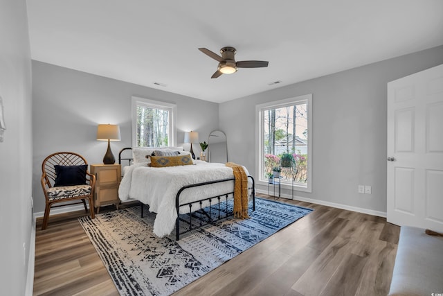 bedroom featuring visible vents, baseboards, ceiling fan, and wood finished floors