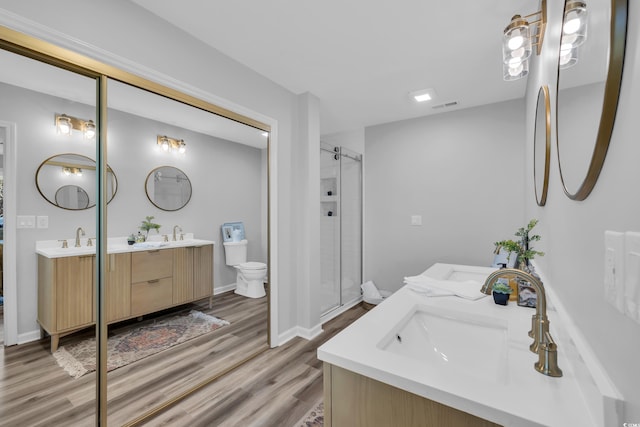 full bathroom featuring a sink, two vanities, wood finished floors, visible vents, and a stall shower