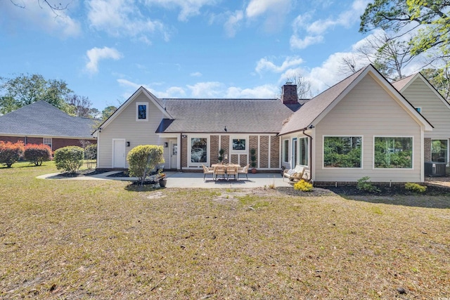 back of property with a chimney, a patio area, central air condition unit, a yard, and a shingled roof