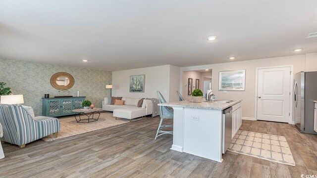 4481 E Coast Ln, Shallotte, NC 28470 - kitchen with stainless steel appliances, wallpapered walls, light wood finished floors, a kitchen bar, and open floor plan