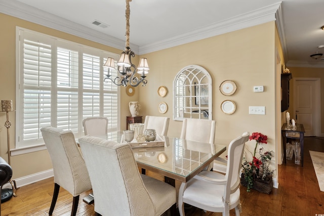 dining room with a notable chandelier, plenty of natural light, hardwood / wood-style floors, visible vents, and ornamental molding