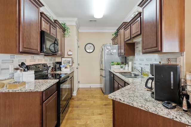kitchen featuring visible vents, light wood-type flooring, a sink, backsplash, and black appliances