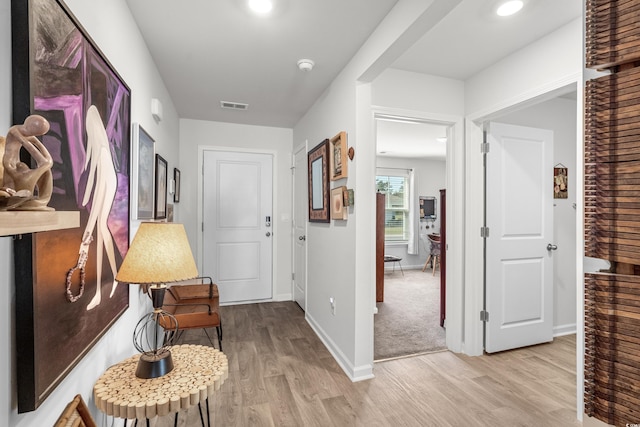 hall featuring visible vents, light wood-type flooring, and baseboards