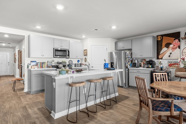 kitchen with a kitchen bar, visible vents, light countertops, stainless steel appliances, and gray cabinetry
