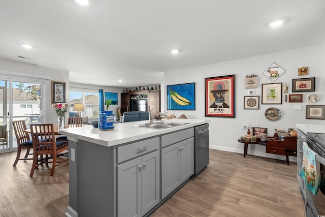 kitchen featuring dishwasher, a sink, light countertops, gray cabinetry, and light wood-style flooring