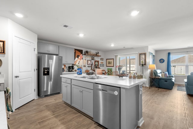 kitchen featuring visible vents, gray cabinets, appliances with stainless steel finishes, a sink, and light countertops