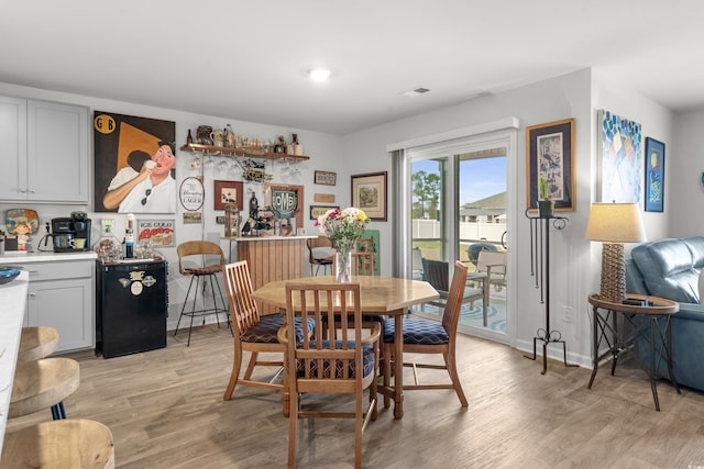 dining room with light wood finished floors, visible vents, and baseboards