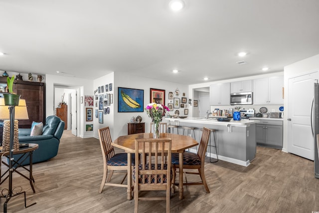 dining space with recessed lighting, light wood-type flooring, and baseboards