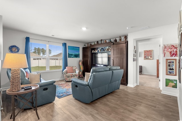 living area with light wood finished floors, visible vents, and baseboards