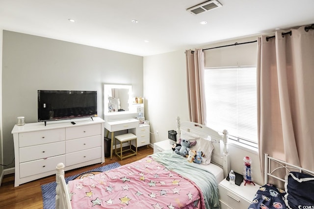 bedroom with baseboards, visible vents, and wood finished floors