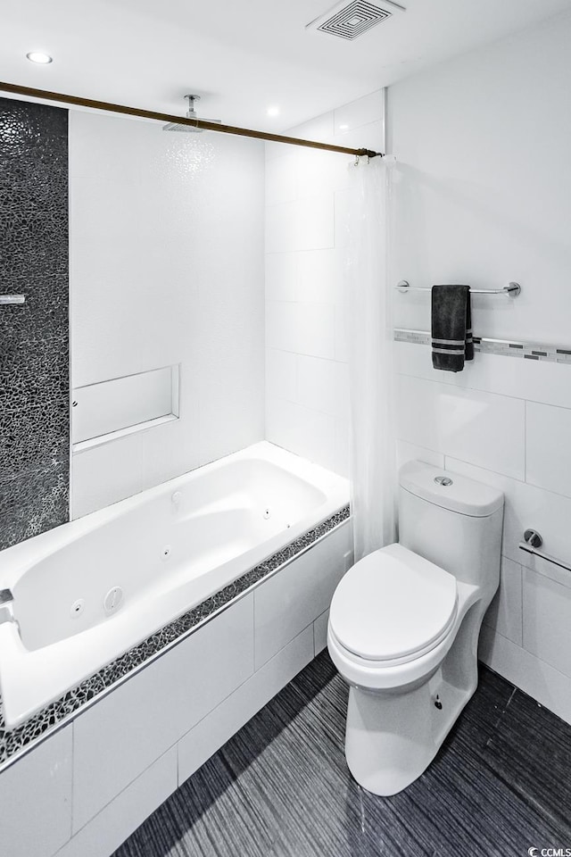 bathroom featuring tile walls, visible vents, toilet, and a combined bath / shower with jetted tub