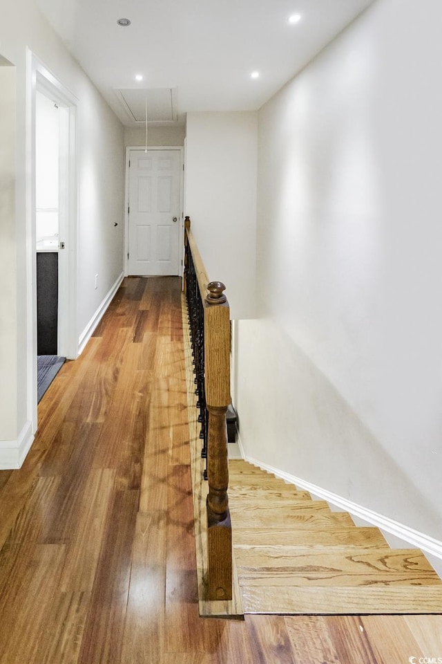 hall with baseboards, an upstairs landing, wood finished floors, and attic access