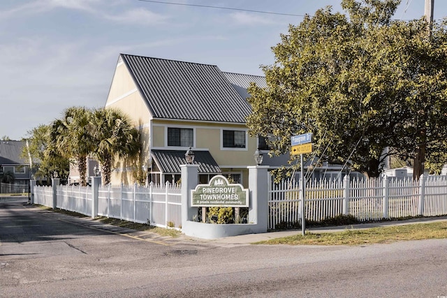 view of front facade with stucco siding, fence, and metal roof