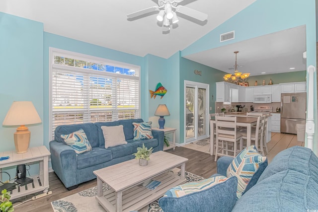 living area featuring light wood finished floors, lofted ceiling, baseboards, ceiling fan with notable chandelier, and visible vents
