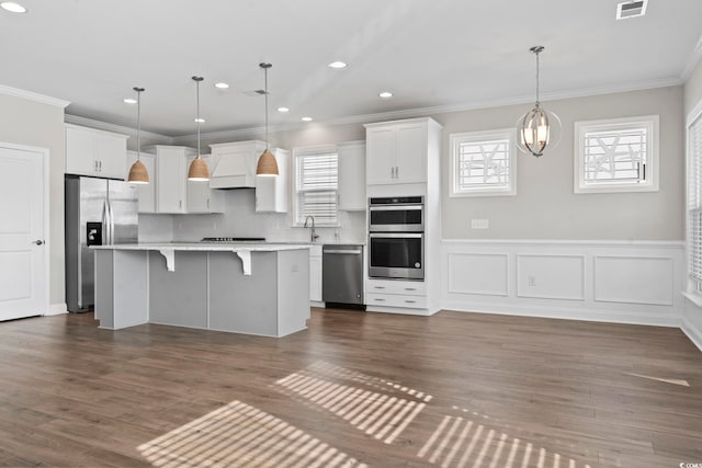 5885 Ledro Ln, Myrtle Beach, SC 29572 - kitchen featuring appliances with stainless steel finishes, a breakfast bar, white cabinets, a kitchen island, and light countertops