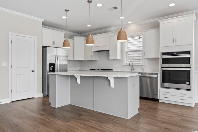 5885 Ledro Ln, Myrtle Beach, SC 29572 - kitchen with stainless steel appliances, a center island, crown molding, white cabinets, and backsplash