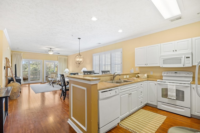 kitchen with visible vents, a sink, a peninsula, open floor plan, and white appliances