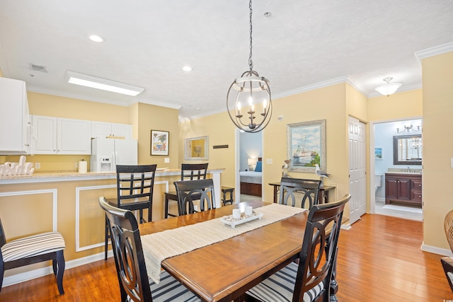 dining space with an inviting chandelier, ornamental molding, visible vents, recessed lighting, and light wood finished floors
