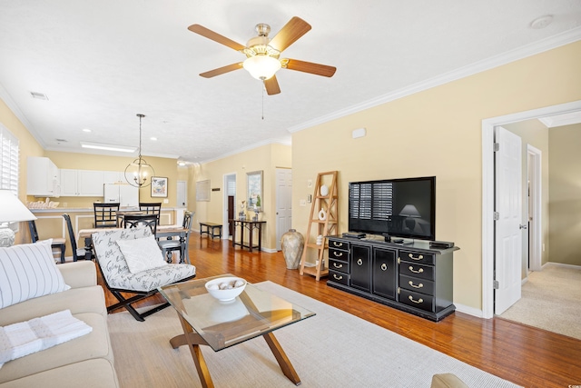 living room featuring crown molding, a ceiling fan, wood finished floors, and visible vents