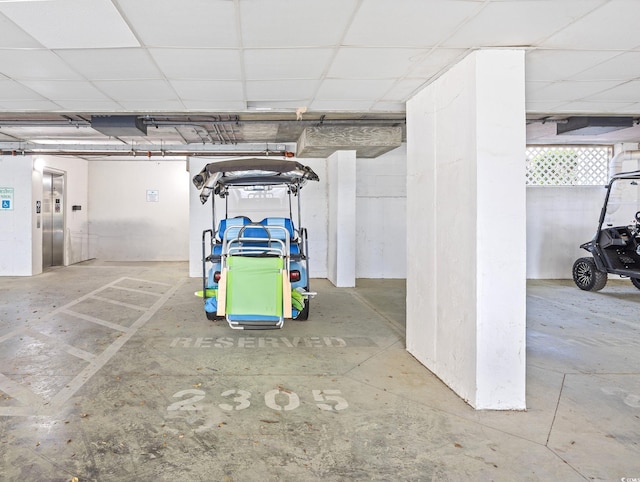 below grade area with a garage, elevator, and a drop ceiling