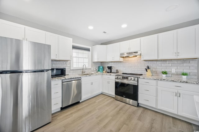 kitchen with a sink, decorative backsplash, stainless steel appliances, white cabinetry, and under cabinet range hood