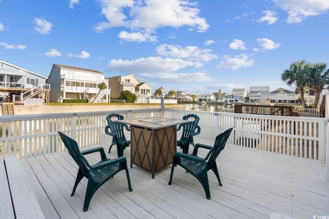 wooden terrace featuring outdoor dining area, a residential view, and a water view