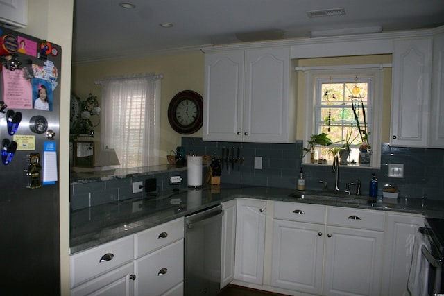 kitchen featuring stainless steel dishwasher, tasteful backsplash, a sink, stove, and freestanding refrigerator