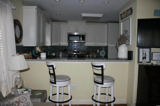 kitchen featuring backsplash, a kitchen bar, and appliances with stainless steel finishes