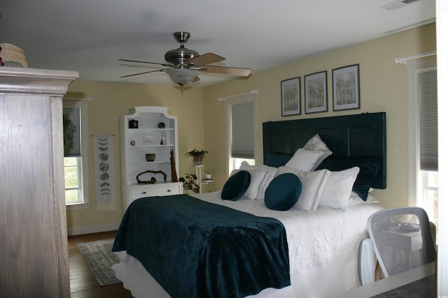 bedroom with a ceiling fan, wood finished floors, and multiple windows