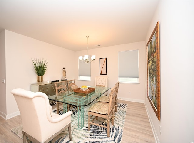 dining room featuring light wood-style floors, baseboards, and a notable chandelier